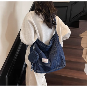 Detail of dark blue denim tote bag with white stitching and round pouch accessory
