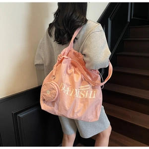 Detailed shot of a pink drawstring tote bag with letter print and a matching coin purse