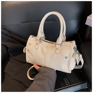Dettaglio della pelle martellata e dei rivetti sulla borsa a bauletto color bianco crema