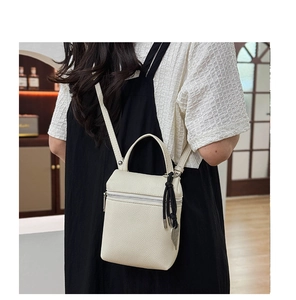 Détail du sac carré en cuir grainé blanc crème avec breloque noire et fermeture éclair argent