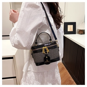 Detail of black crossbody box bag with gold hardware and logo tag on a model