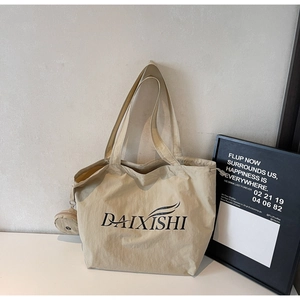 Detail of beige canvas tote bag with black logo lettering and side coin purse attachment