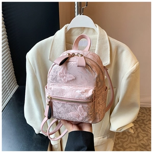 Detail of pink vintage backpack featuring 3D butterfly appliques and textured fabric