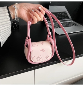 Close-up of pink saddle bag with bear motif and embossed lettering on matte leather