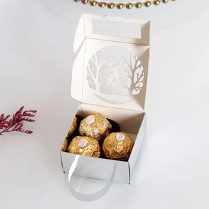 Close-up of laser-cut reindeer and forest patterns on a white Christmas candy gift box