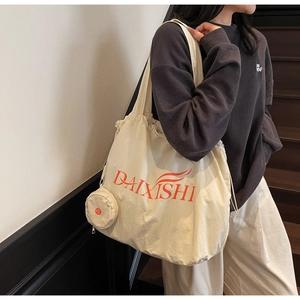 Detail of cream large canvas tote bag with hanging round coin purse and orange text