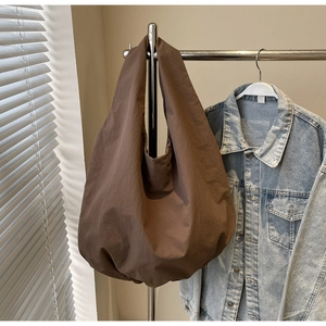 Dettaglio di una grande borsa tote marrone caffè con trama stropicciata su un rack