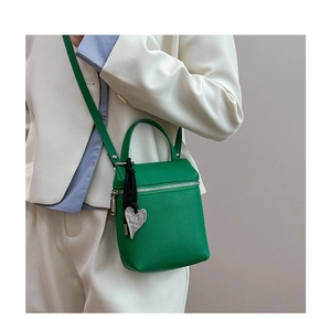 Vue détaillée du sac bandoulière vert vif avec cuir grainé et pendentif cœur argenté