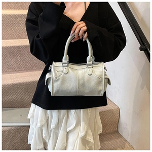 Dettaglio borsa a mano in pelle beige con rivetti argentati e tasche laterali