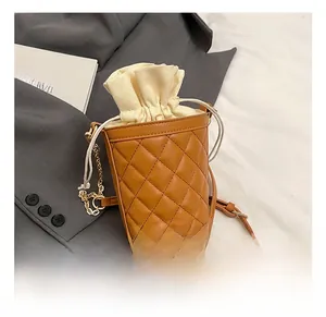 Detail of brown quilted bucket bag featuring a cream canvas drawstring and gold chain strap