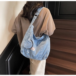 Detail of light blue denim tote bag with detachable mini coin purse and wide strap