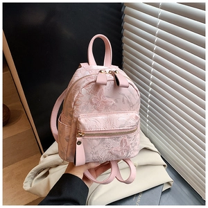 Detail of pink mini backpack featuring 3D butterfly and floral embroidery and texture