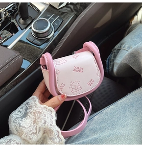 Detail of pink mini saddle bag with embossed bear pattern held in a car setting