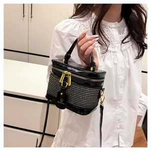 Detail of a chic black textured box bag featuring gold double zippers and a leather logo tag