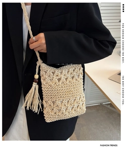 Détail du motif tissé à la main avec glands et perles en bois sur un sac en paille crème