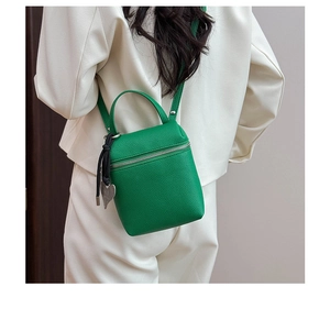 Detail of green litchi texture mini bag with silver zipper and heart pendant charm