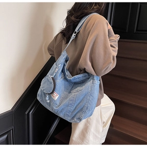 Macro shot of blue washed denim hobo bag featuring functional pockets and round mini pouch