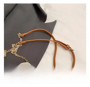 Detail of the adjustable brown leather strap with gold chain and cream canvas bucket bag