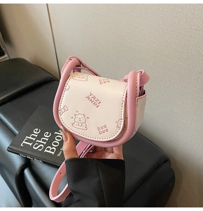 Macro detail of pink saddle bag with bear print and brand engraving on the leather cover