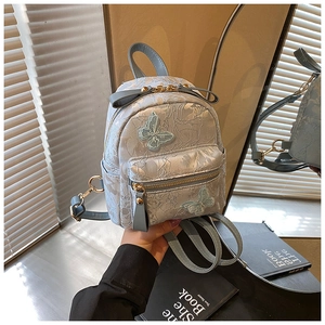 Detail of light blue jacquard mini backpack with floral texture and butterfly patches