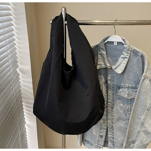 Dettaglio della grande borsa tote nera minimalista con tessuto resistente e design curvo