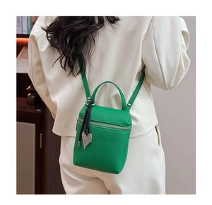 Detail of emerald green lychee pattern crossbody bag with a heart charm and silver zipper