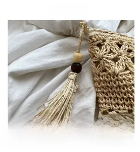 Détail de la texture d'un sac en paille tissée avec de longs glands et perles en bois