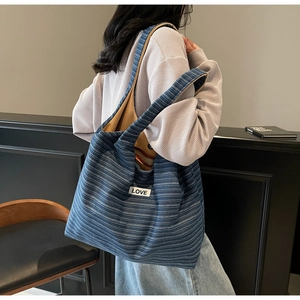 Detail view of large navy striped canvas tote bag with white LOVE patch on wide shoulder strap