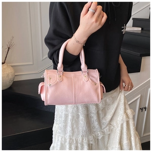 Dettaglio della borsa a bauletto in pelle rosa con manici tondi e rivetti decorativi