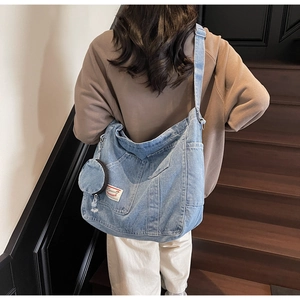 Close-up of light blue denim tote bag with mini coin purse on wooden stairs