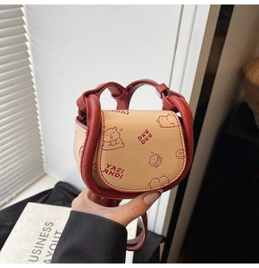 Detail of mini saddle bag with red contrast handle and cute cartoon bear patterns
