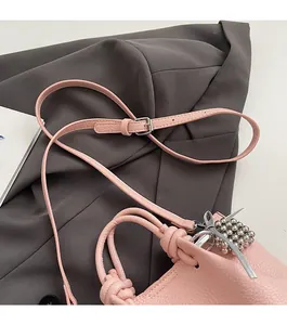 Detail of light pink pebble leather bag with knot handle and metallic spike charm