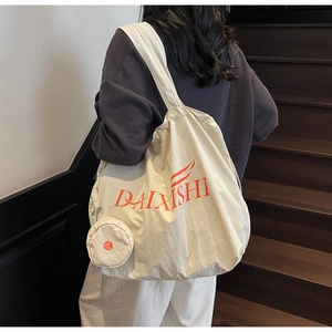 Close-up of cream canvas tote bag with hanging coin purse and orange logo detail