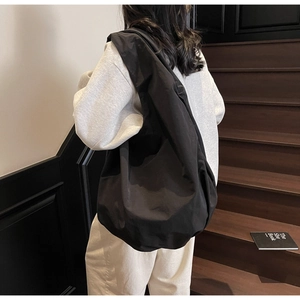 Dettaglio di una borsa tote nera in nylon che mostra la consistenza morbida e la grande capacità