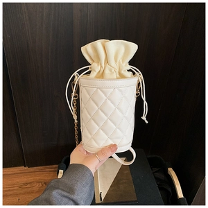 Detail of cream drawstring bucket bag with quilted stitching and gold chain strap