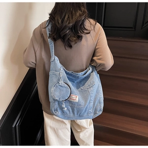 Detail of light blue denim tote bag with round coin purse and red logo label