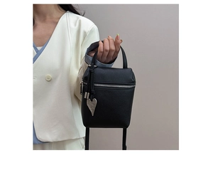 Vue détaillée d'un sac à main noir en cuir grainé avec pendentif en forme de cœur argenté