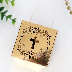 Detail of golden hollow-out cross gift box with elegant laser-cut floral wreath and handle
