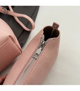 Detailed close-up of smooth silver zipper on pink pebble leather crossbody bag