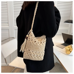 Detail of beige crochet phone bag featuring hollow floral pattern and ethnic tassel charm