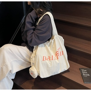Detail of a large cream canvas tote bag with orange DAIXIHI logo and small round coin purse