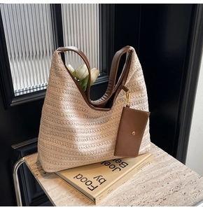 Detail of minimalist straw tote bag with brown leather handles and small pouch