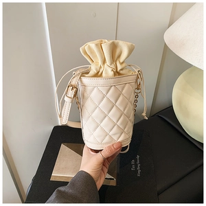 Detail of cream quilted bucket bag featuring a drawstring canvas lining and gold chain strap