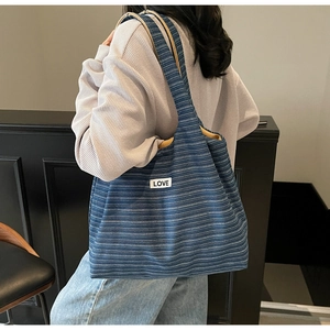 Detail of blue striped canvas tote bag showing LOVE patch and ginger yellow lining texture