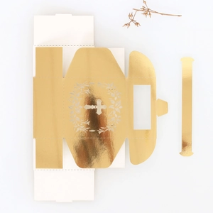 Detailed laser-cut hollow cross and laurel wreath on golden candy gift box for weddings