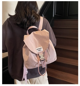 Detail of light purple nylon drawstring backpack with buckle and logo tag shown on model