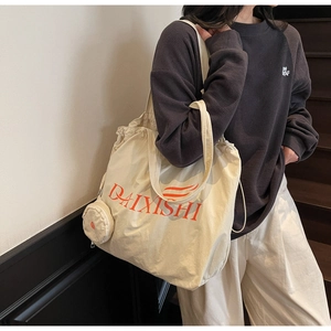 Detail of canvas tote bag with drawstring closure, orange logo, and small coin purse