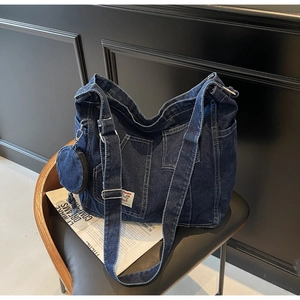 Detail of deep blue washed denim tote bag featuring white contrast stitching and mini pouch