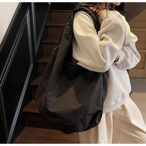Dettaglio di una borsa tote nera minimalista che mostra il nylon morbido e la forma ampia