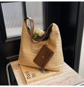 Detail of hand-woven straw tote with brown leather strap and matching small pouch